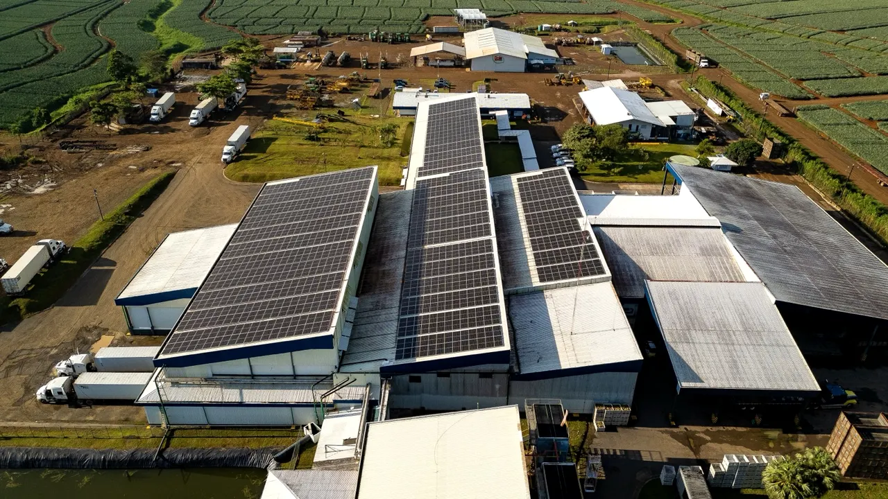 Tres naves industriales con módulos solares en el techo, vistas desde el aire