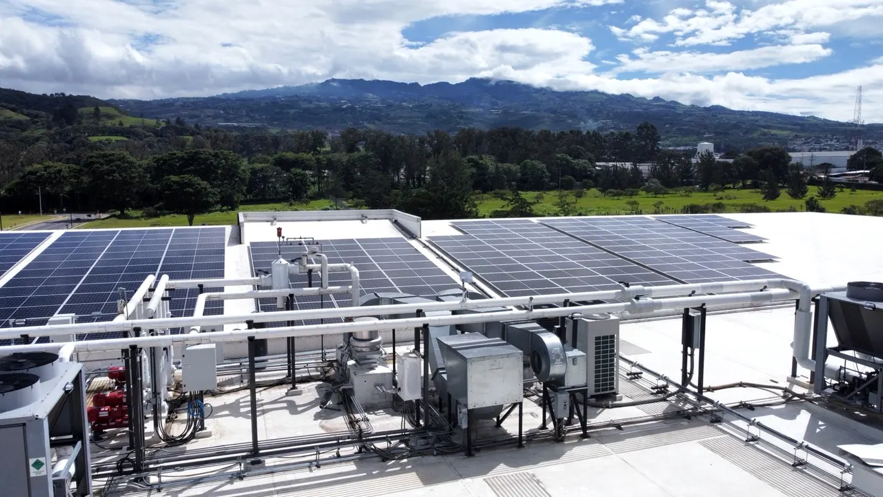 Techo industrial con módulos solares y la cordillera al fondo